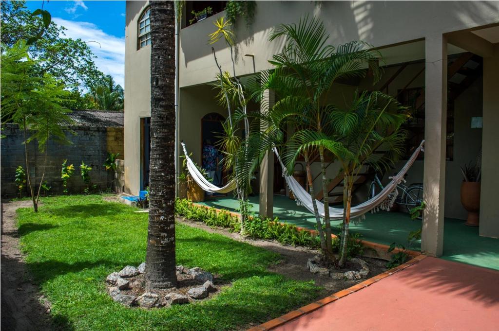 a house with a hammock in the yard at Pousada Do Caju in Nova Viçosa