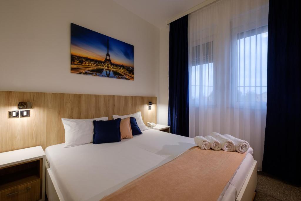 a bedroom with a large white bed and a window at Airport Hotel Garni in Belgrade