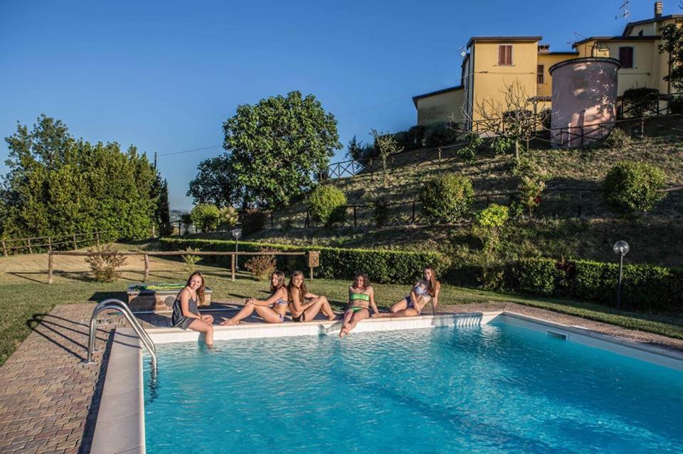 a group of women sitting on the edge of a swimming pool at Il poggio dei tre contadini in Ponte Felcino