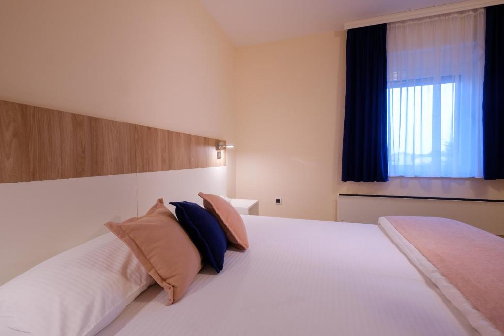 a bedroom with a large white bed with two pillows at Airport Hotel Garni in Belgrade
