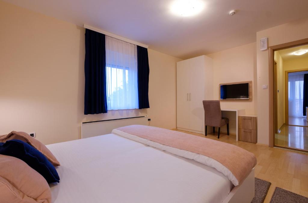 a bedroom with a large white bed and a chair at Airport Hotel Garni in Belgrade