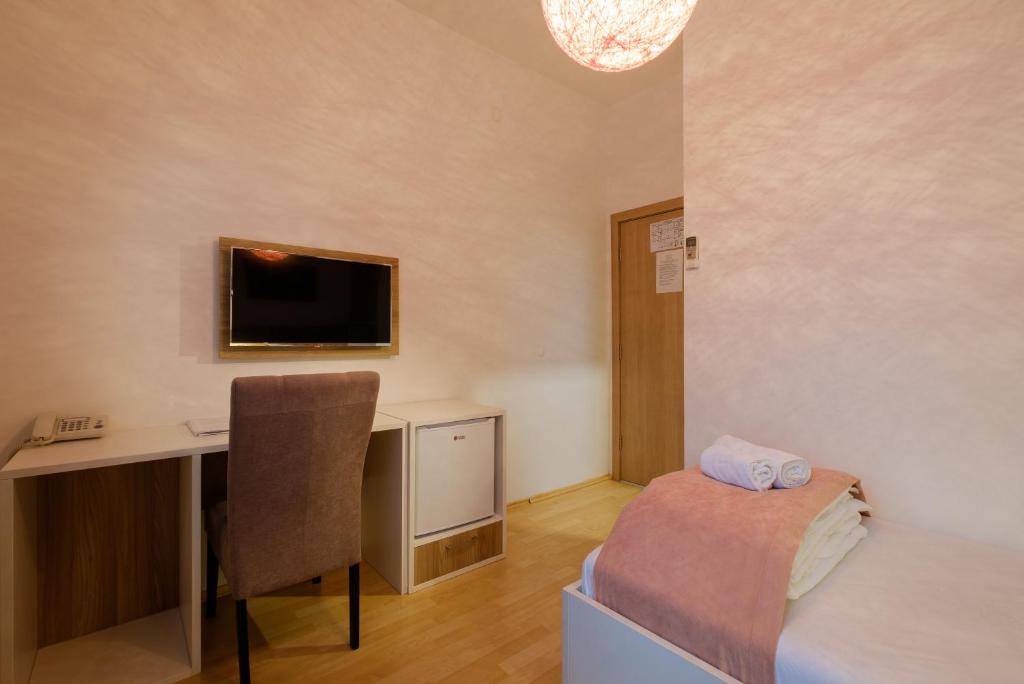 a room with a desk and a bed and a chair at Airport Hotel Garni in Belgrade