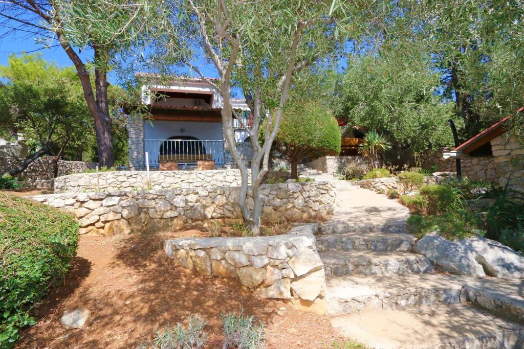 a stone wall and a tree in front of a house at House Silvestra in Borovići