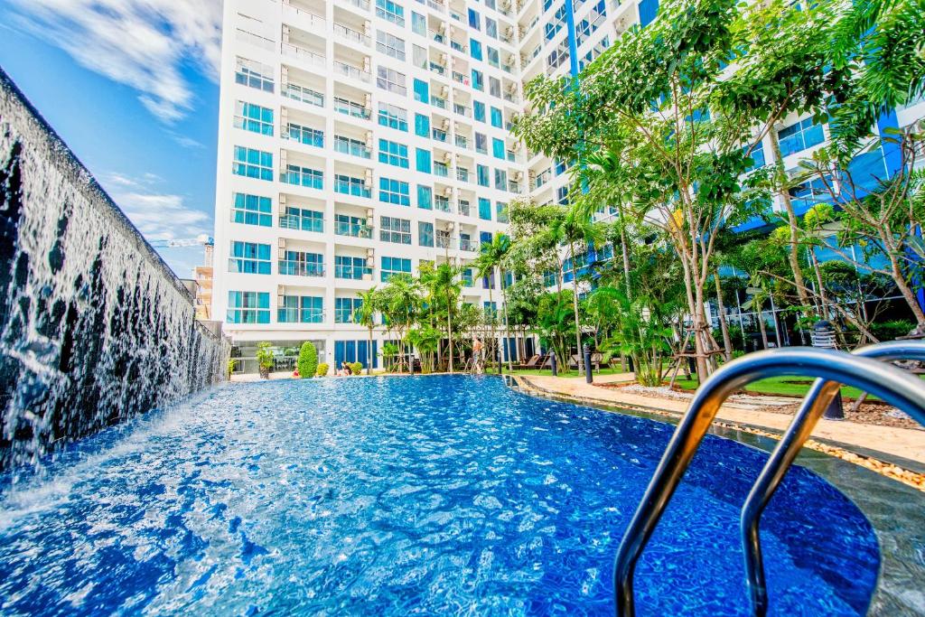a swimming pool with a fountain in front of a building at Nam Talay Jomtien Beach - Rooftop Ocean View - Close to Beach, Pool & Gym in Na Jomtien