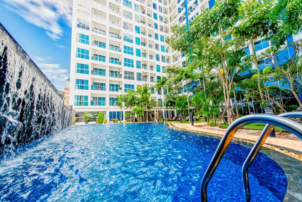 a swimming pool with a fountain in front of a building at Nam Talay Jomtien Beach in Na Jomtien