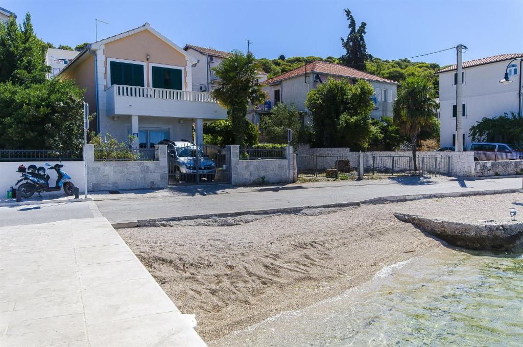 a sandy beach with a house and a motorcycle on it at Apartment Iryna in Rogoznica