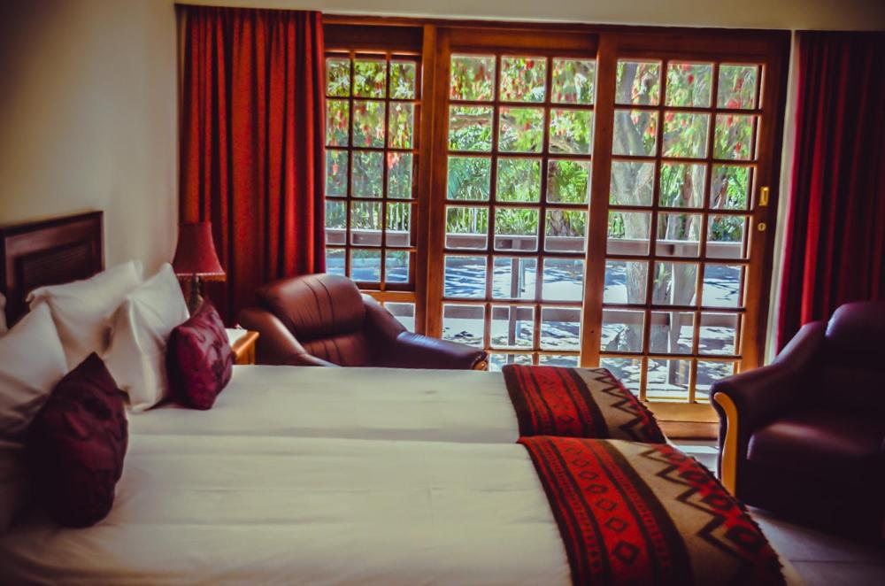 a hotel room with a bed and a large window at Dolliwarie Guesthouse in Panorama