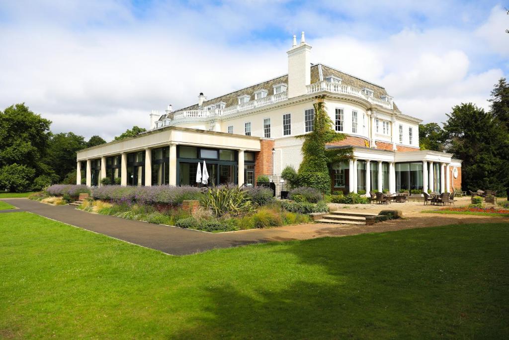 un grand bâtiment blanc avec une pelouse verte dans l'établissement Hotel du Vin Cannizaro House Wimbledon, à Londres