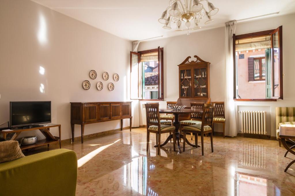 uma sala de estar com uma mesa e cadeiras e uma televisão em Rialto Bridge Large Venetian Style With Lift em Veneza