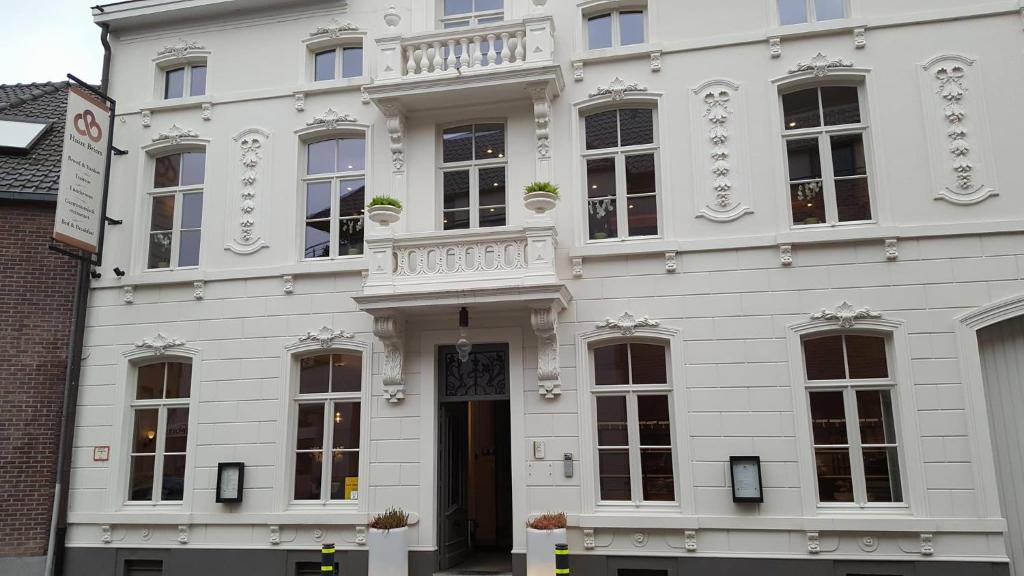 a white building with a door and a balcony at B&amp;B Huize Briers in Bilzen