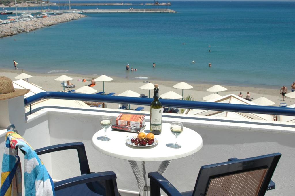 een tafel met een fles wijn en een schaal fruit op een balkon met uitzicht bij Portobelis Apartments in Sitia