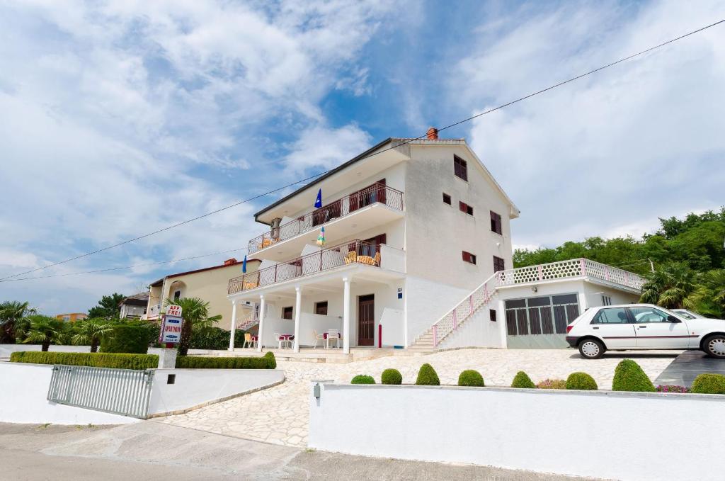 a white building with a car parked in front of it at Apartments Rozaria in Dramalj