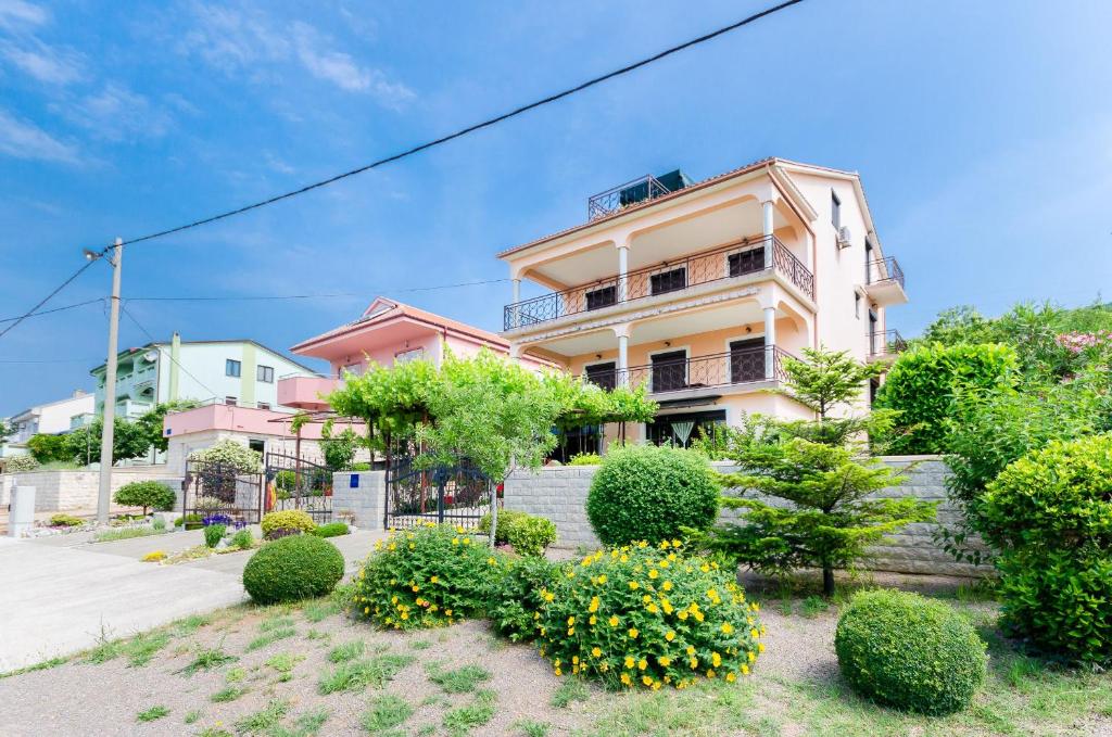 a pink building with bushes in front of it at Apartment Katarina in Crikvenica