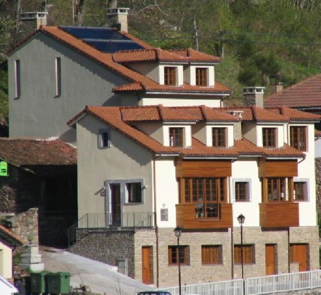 una gran casa blanca con techo rojo en Apartamentos Casa Miño, en Pola de Somiedo