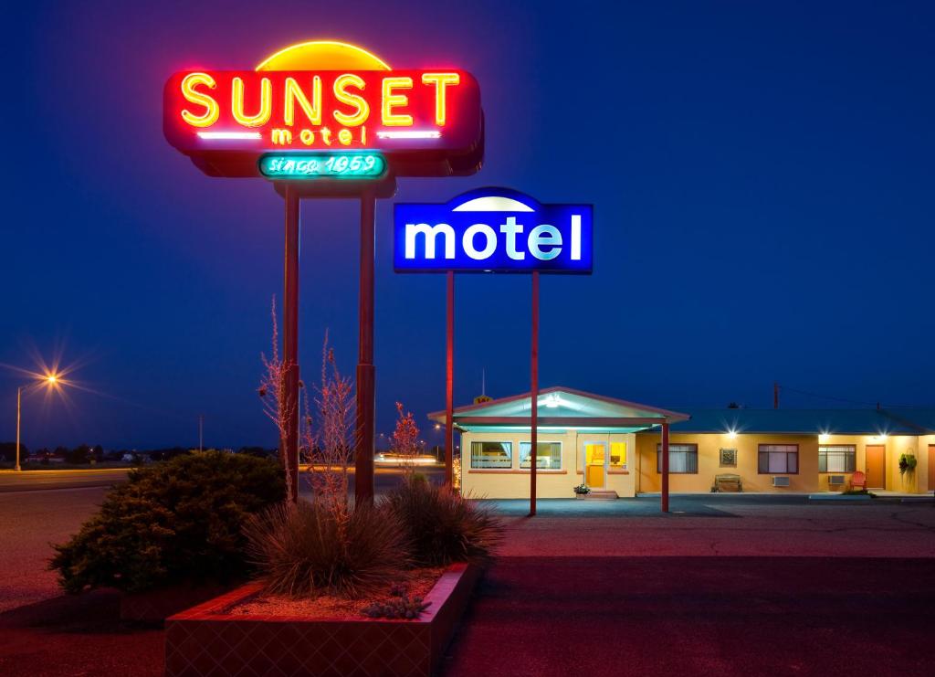 een motel met een bordje voor een motel bij zonsondergang en een motel bij Sunset Motel Moriarty in Moriarty