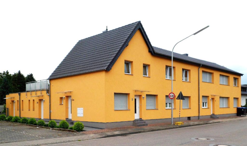 un bâtiment jaune avec un toit noir dans une rue dans l'établissement Ferienwohnung Anke - Apartment 3b, à Heinsberg