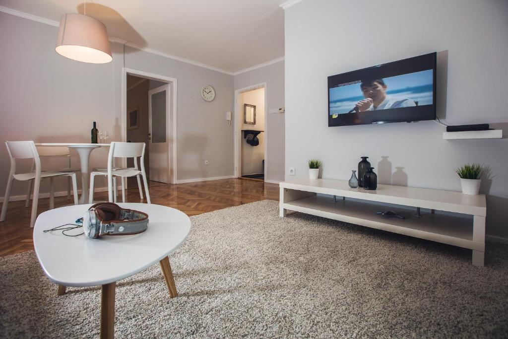 un soggiorno con tavolo e TV a parete di Green Avenue Apartment Zagreb a Zagabria