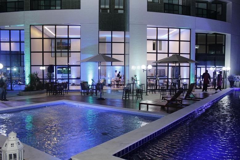 uma piscina num edifício com mesas e guarda-sóis em Flats Rosarinho Prince Prime no Recife