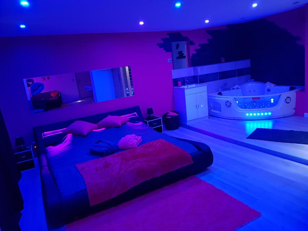 a room with a bed and a tub with purple lights at desirs-spa in Saint-Amarin