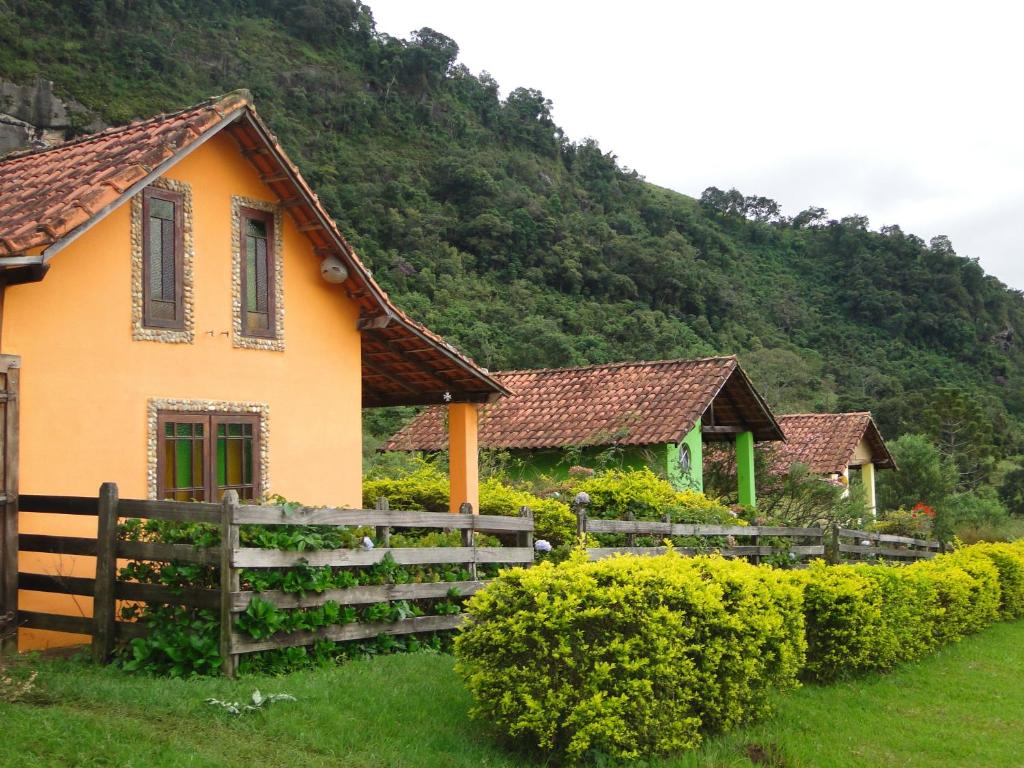 a house with a fence in front of a mountain at Pousada Pé da Mata in Aiuruoca
