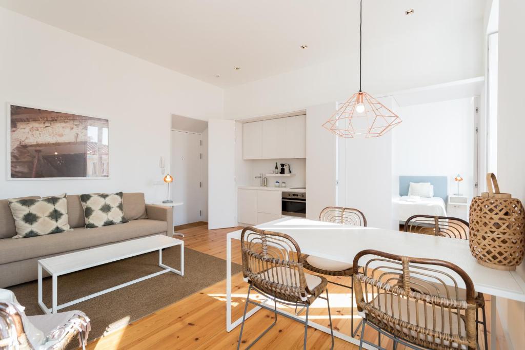uma cozinha e sala de estar com uma mesa branca e cadeiras em Chiado Cozy Apartments - by LU Holidays em Lisboa