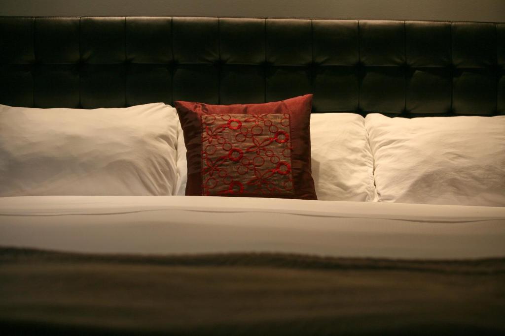 a bed with a red pillow and three pillows at Hotel Metro in London