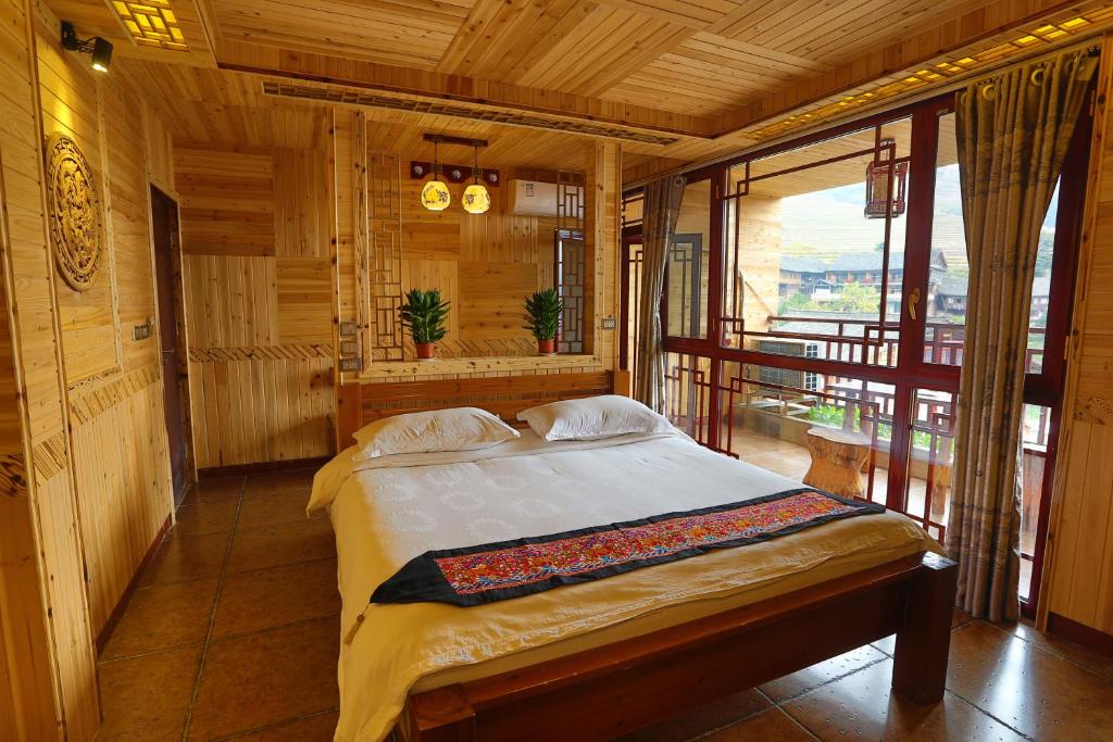 a bedroom with a bed and a large window at Longji Holiday Hotel in Longsheng