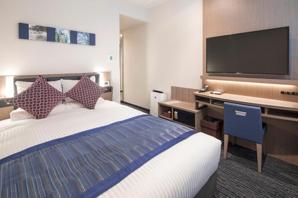 a hotel room with a bed and a desk with a flat screen tv at Hotel Mystays Gotanda Station in Tokyo