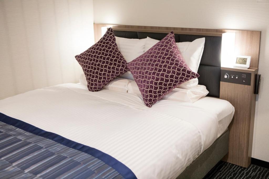 a bed with four pillows on top of it at Hotel Mystays Gotanda Station in Tokyo