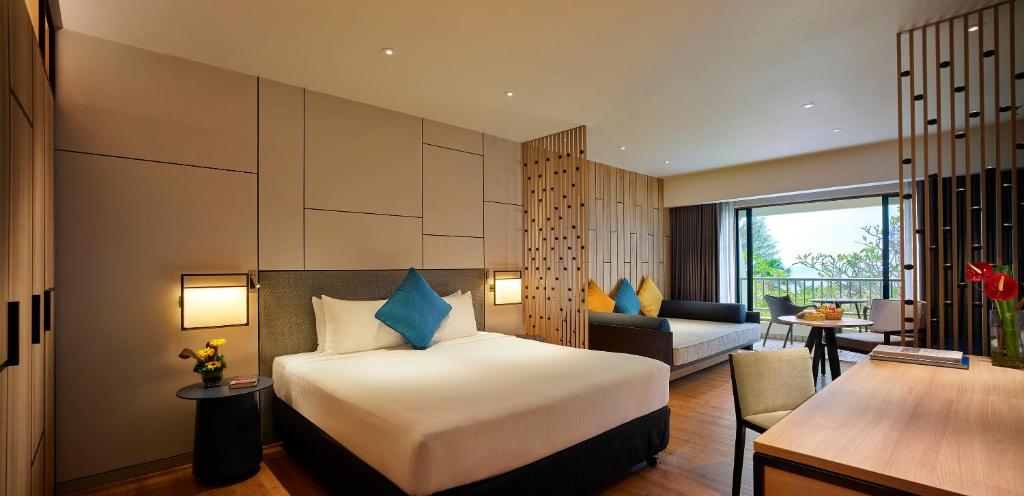 a hotel room with a bed and a living room at PARKROYAL Penang Resort in Batu Ferringhi