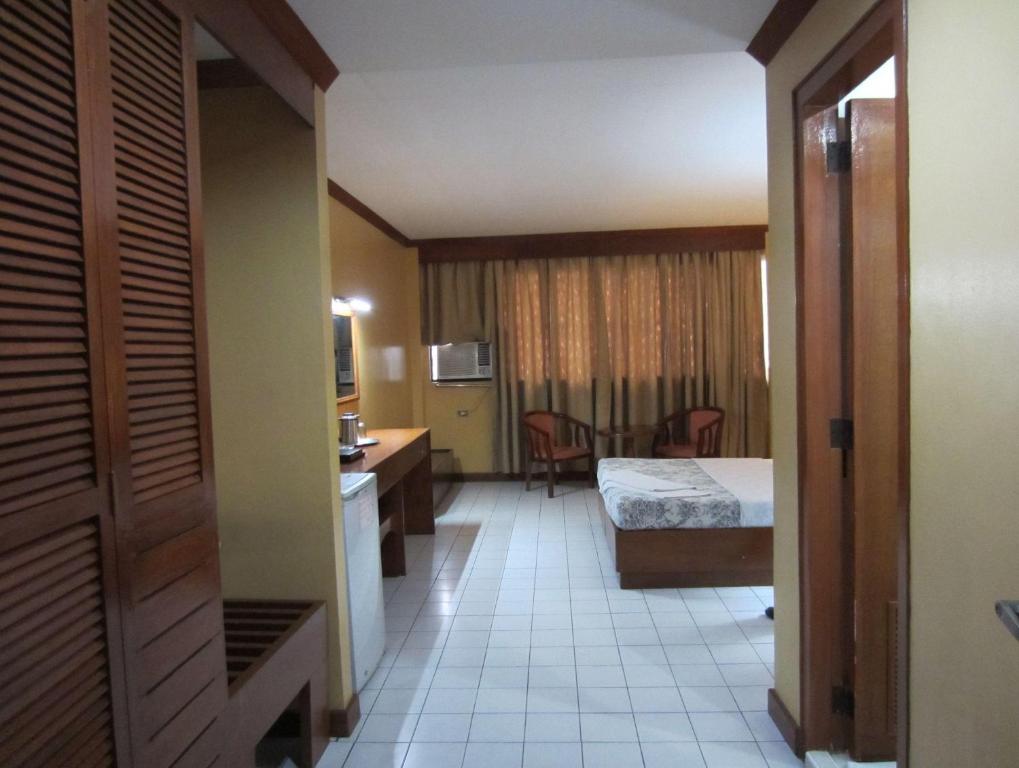 Cette chambre comprend un lit et un bureau. dans l'établissement Hotel Soriente, à Manille