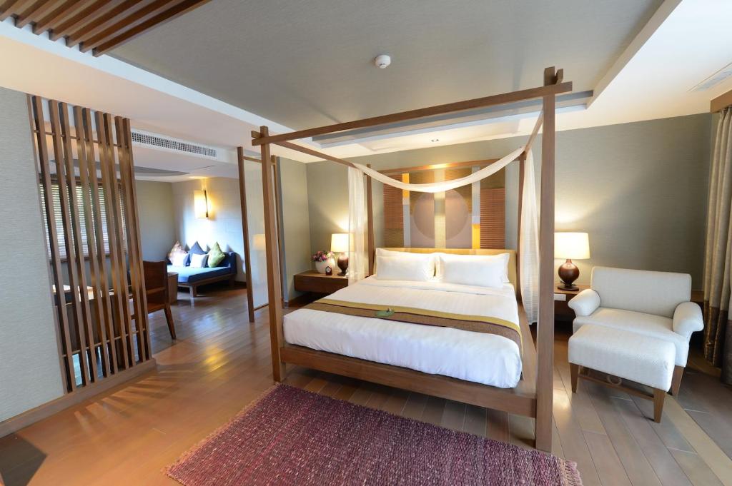 A warm bedroom with a four-poster canopy bed, sitting area and wood floors.