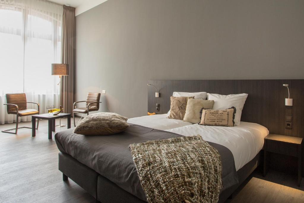 a bedroom with a large bed and a living room at Hotel Bladel in Bladel