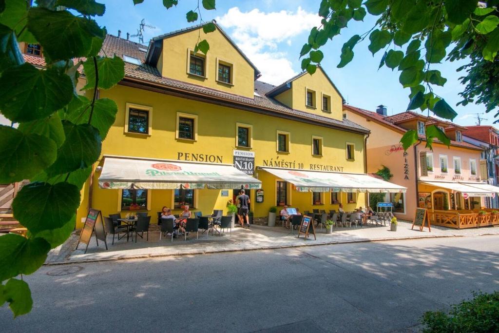 a yellow building with tables and chairs in front of a street at pension N.10 in Frymburk