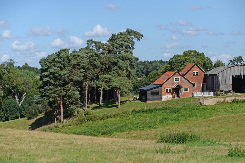 una casa en una colina con un granero y árboles en The Parlour en Freston