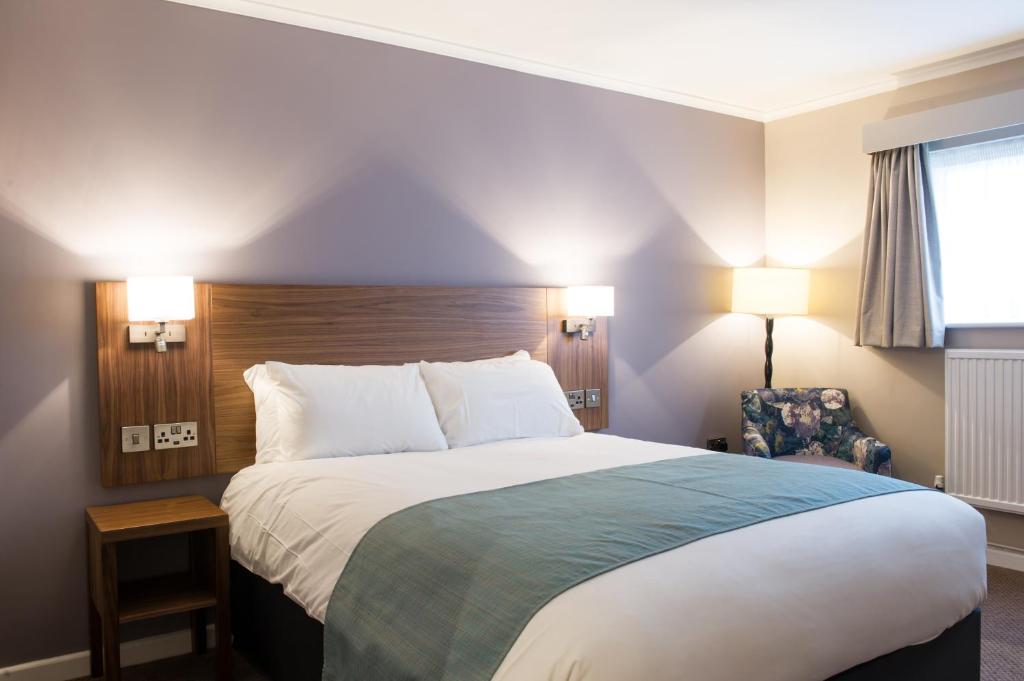 a hotel room with a large bed and a chair at The Beach Arms by Innkeeper's Collection in Oakley