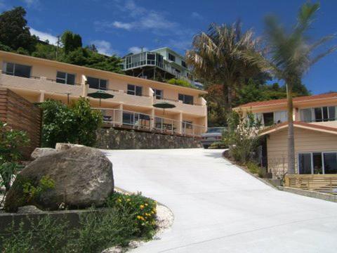 a parking lot in front of a building with a rock at Paku Lodge Resort in Tairua
