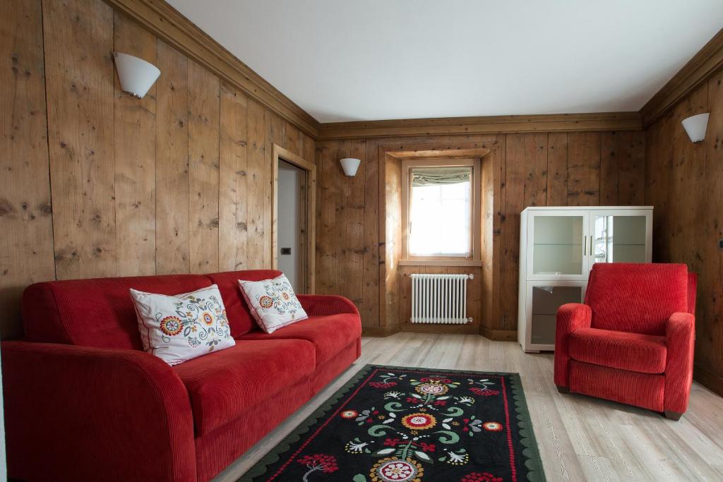 een woonkamer met een rode bank en een stoel bij Casa del Sol Apartaments in Bormio