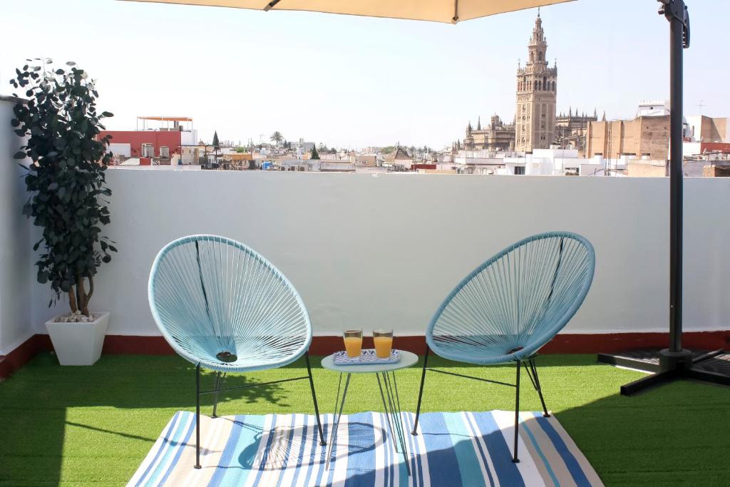 two chairs and a table on a balcony with a view at Ático céntrico con vistas in Seville