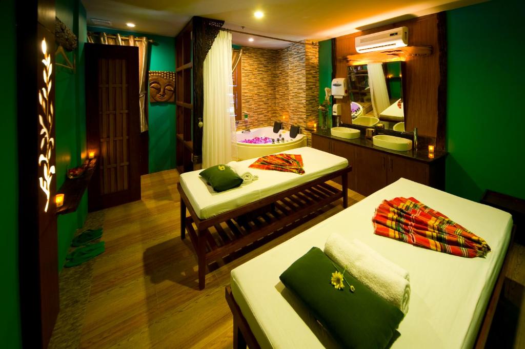 a green room with two beds and a mirror at Skinetics Wellness Center Boutique Hotel in Iloilo City