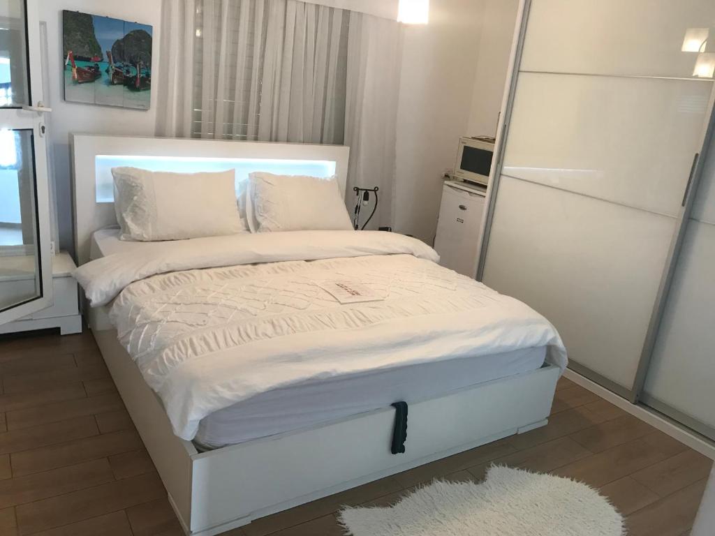 een wit bed met witte lakens en kussens in een slaapkamer bij Charming Unit with Pool and Great Amenities in Rishon LeẔiyyon