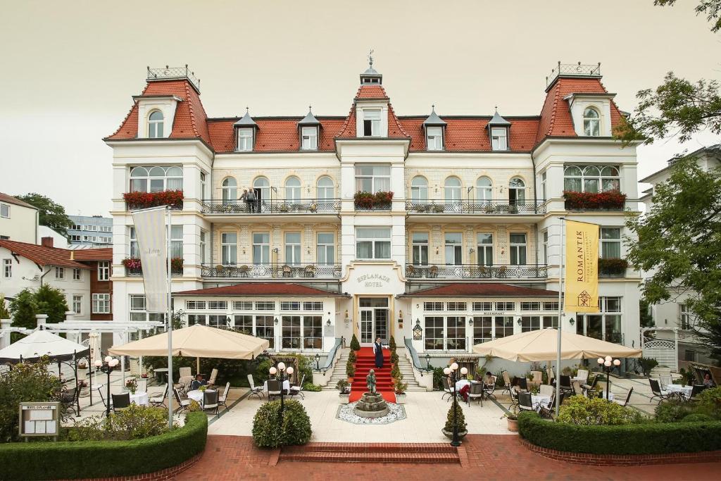 un gran edificio con mesas y sombrillas delante en SEETELHOTEL Villa Esplanade mit Aurora en Heringsdorf