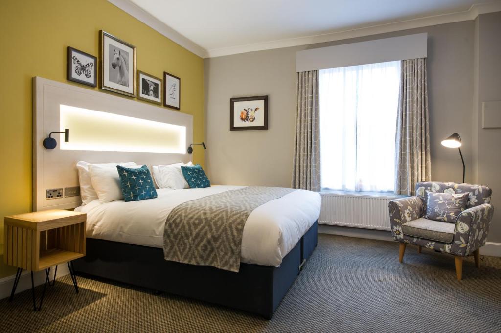 een hotelkamer met een bed en een stoel bij The Dun Cow by Innkeeper's Collection in Rugby