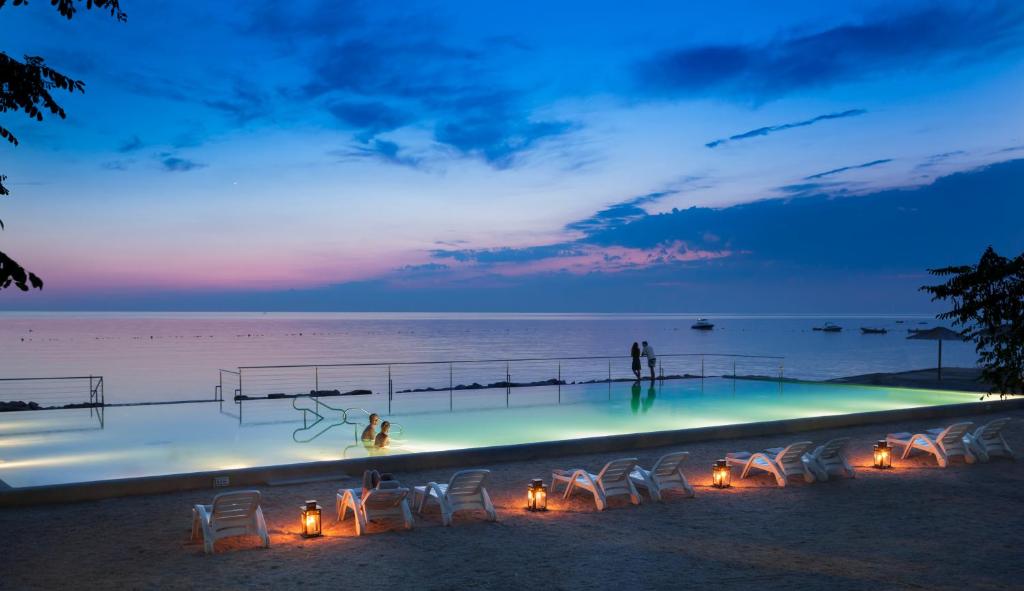 basen z krzesłami i oświetleniem na plaży w obiekcie Aminess Planet Camping Holiday Homes Maravea w mieście Novigrad