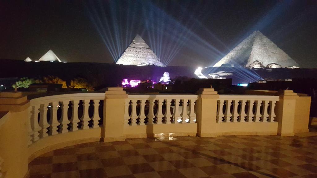 a white fence with pyramids in the background at night at Royal Pyramids Inn in Cairo