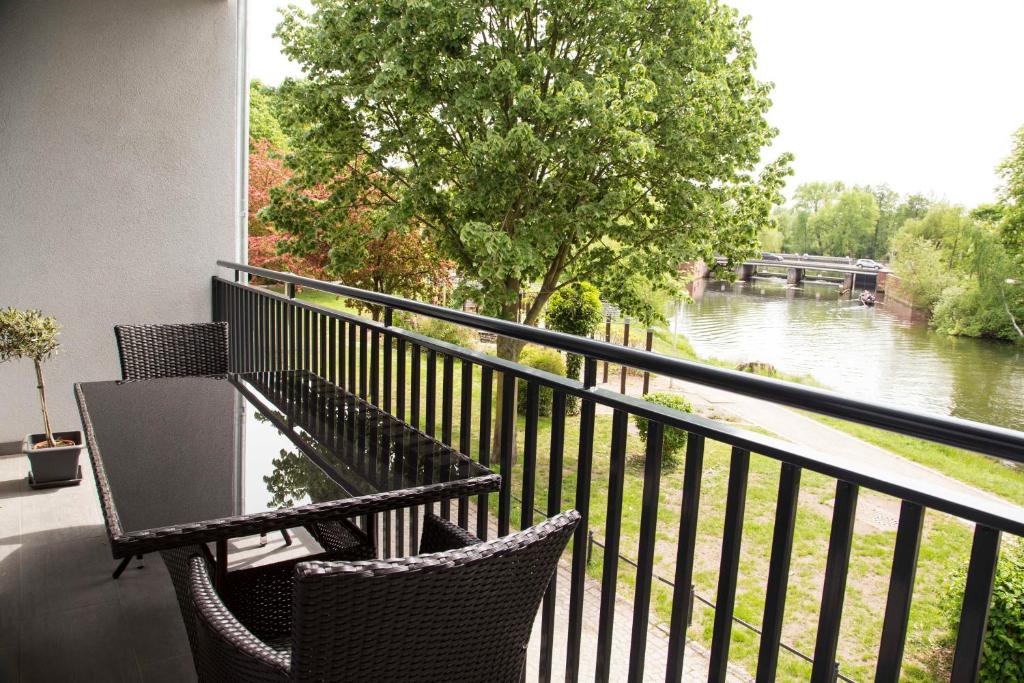 een balkon met een tafel en stoelen en uitzicht op een rivier bij Spreehaus-Apartments in Lübben