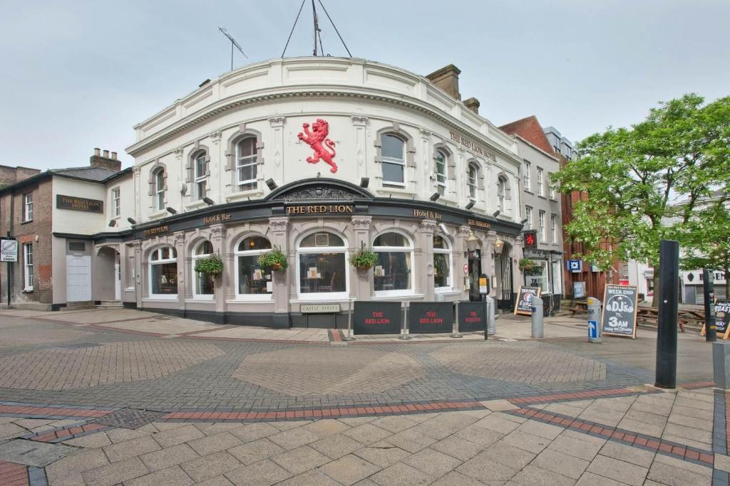 Un grande edificio bianco con una donna rosa sopra di The Red Lion Hotel a Luton