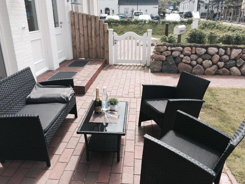 eine Terrasse mit schwarzen Stühlen und einem Tisch mit Flaschen darauf in der Unterkunft Robbe in Hörnum