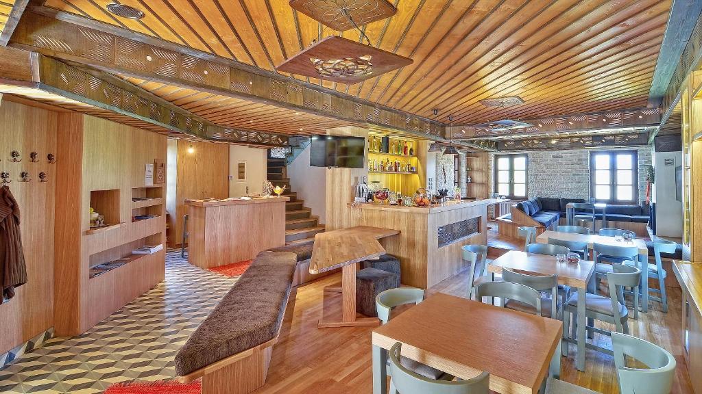 Dilofo Hotel Luxury Suites في ذلوفو: مطعم بسقوف خشبية وطاولات وكراسي