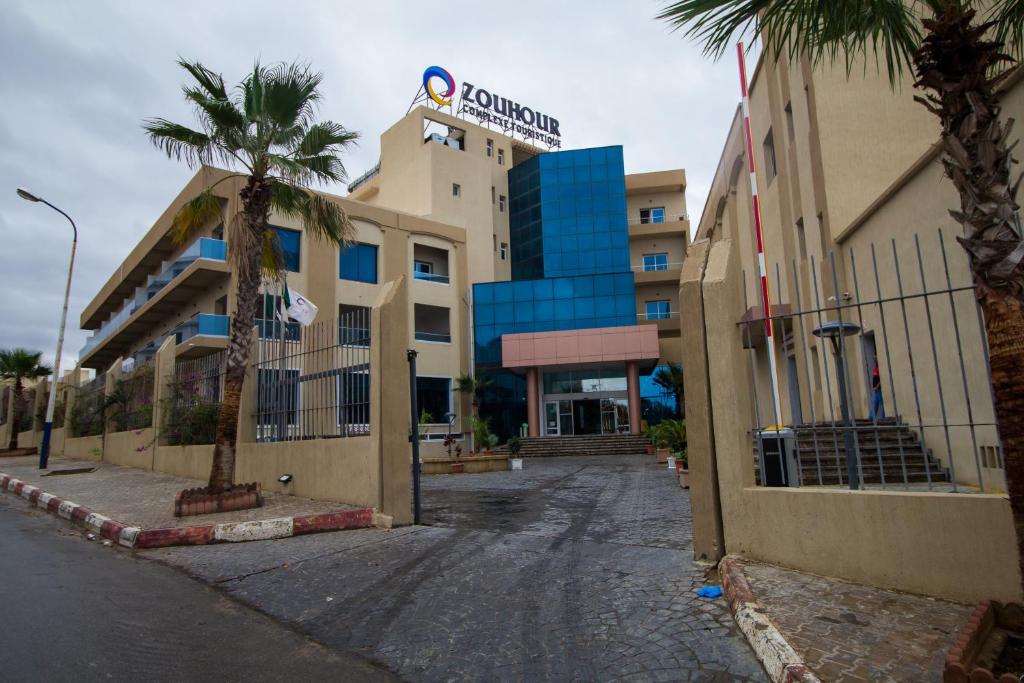 una strada vuota di fronte a un hotel con palme di Complexe Touristique BouZour a Mostaganem